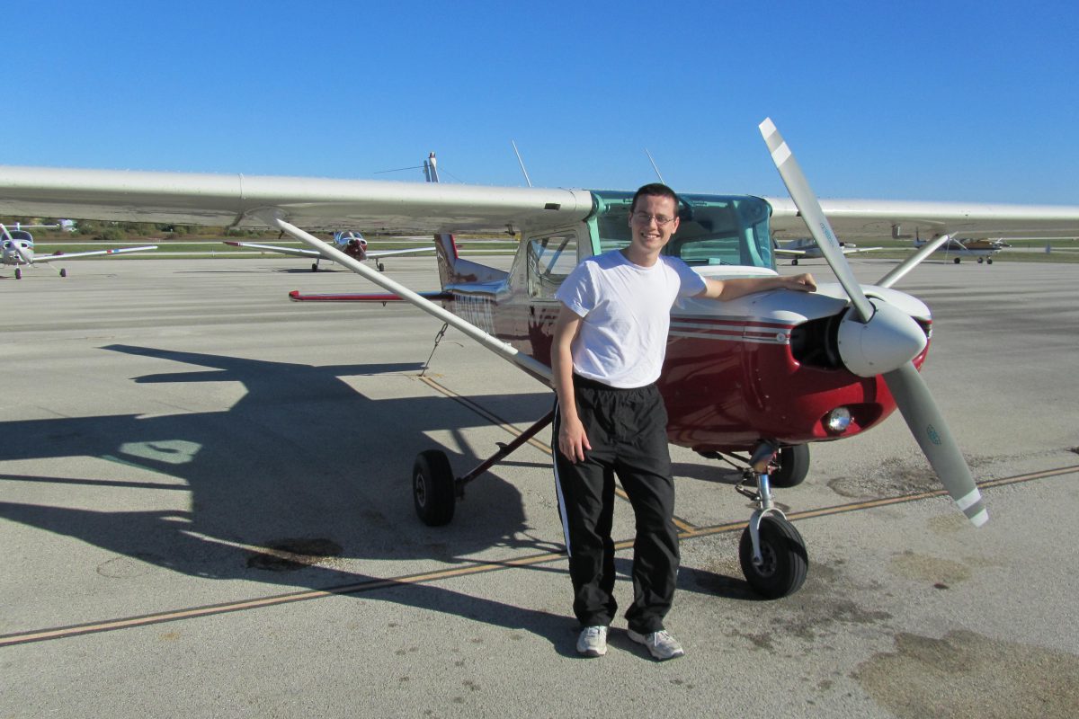 Student posing next to airplane